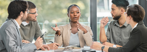 Five individuals in a meeting with the woman in the middle talking to the group