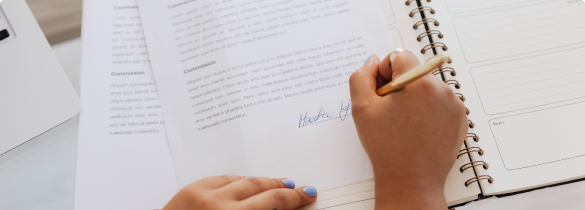 A closeup of a woman's hand signing document