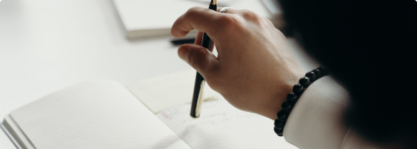 Close up of a woman's hand holding a pen over a notebook