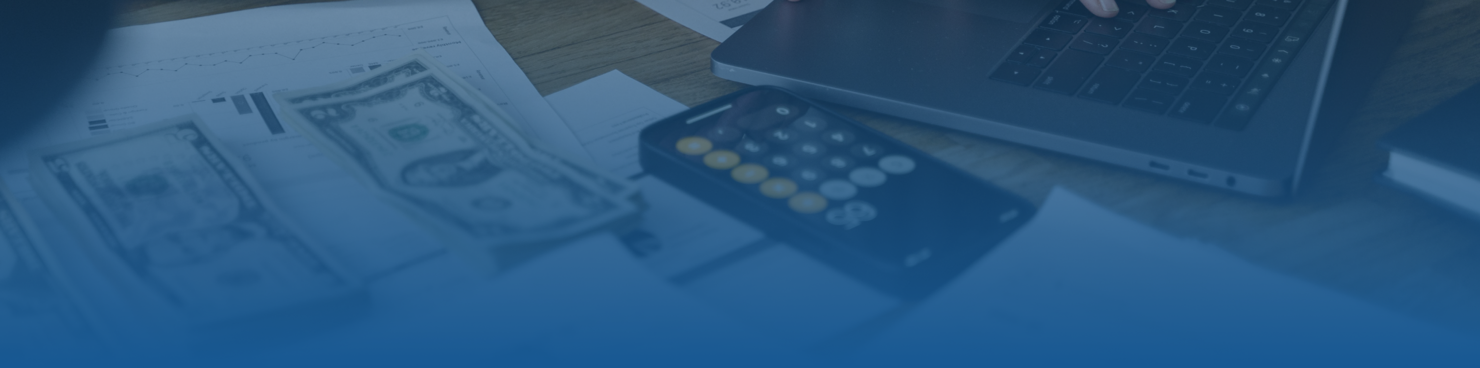 Blue tint frame hero image with a table that has a calculator, cash, and a laptop on it